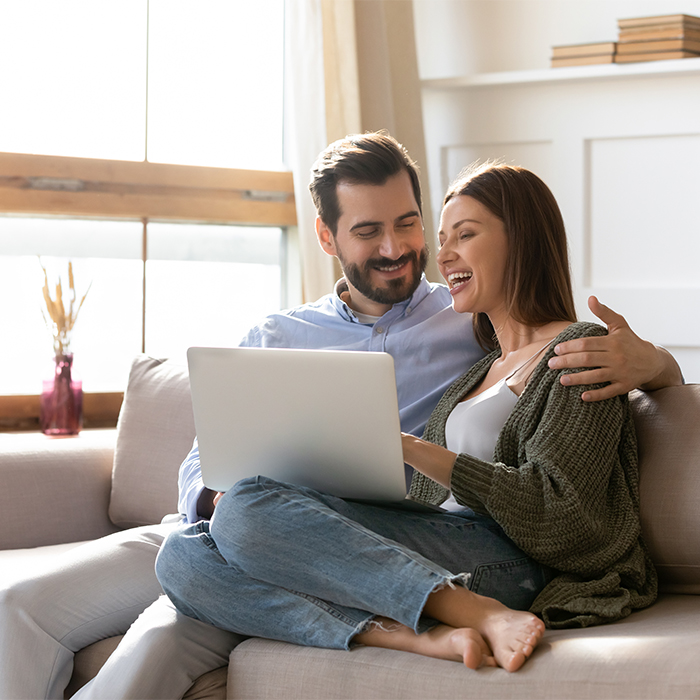 Couple on couch looking at laptop